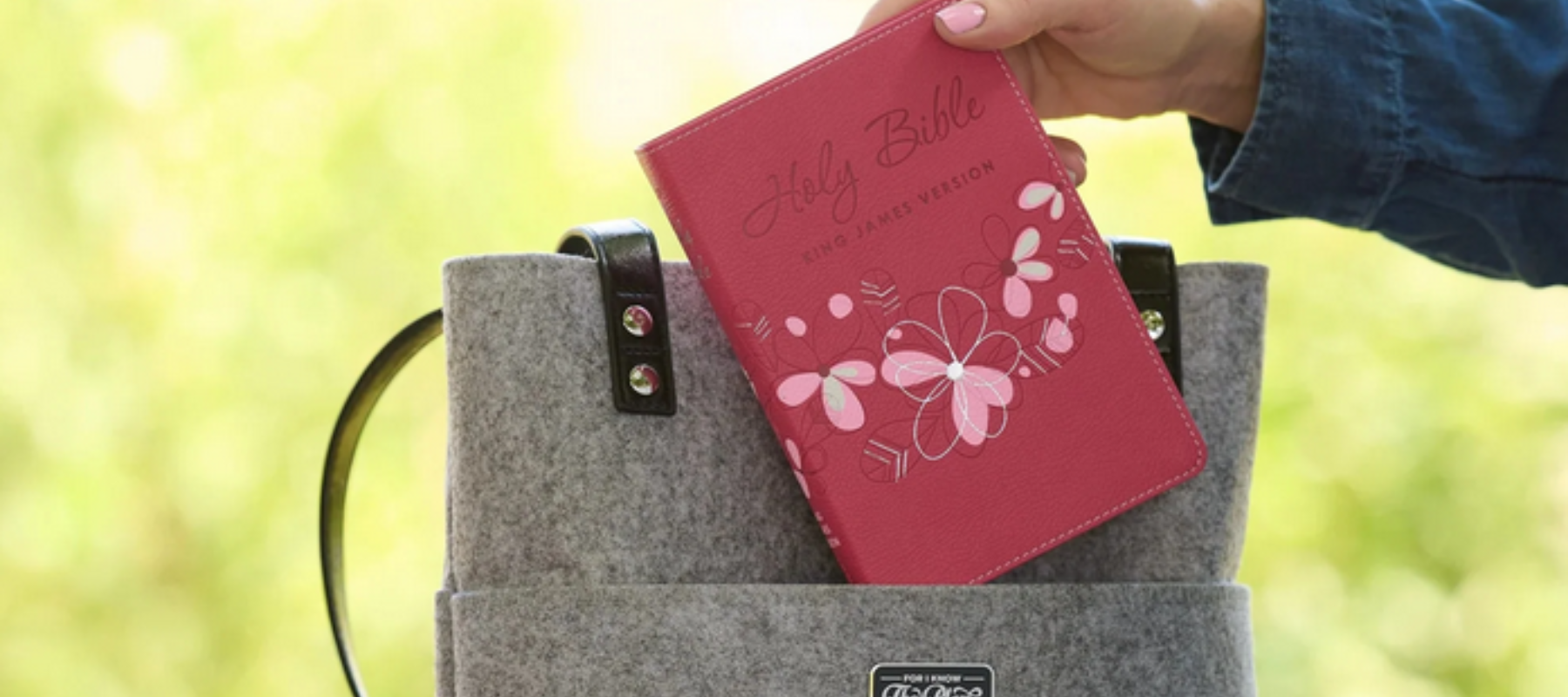 Person placing a teen Bible with several colors on it into a luxury bag